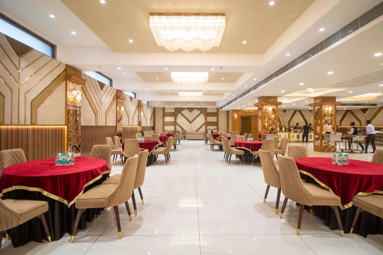 Dining hall with round tables in red cloth, cushioned chairs and chandeliers