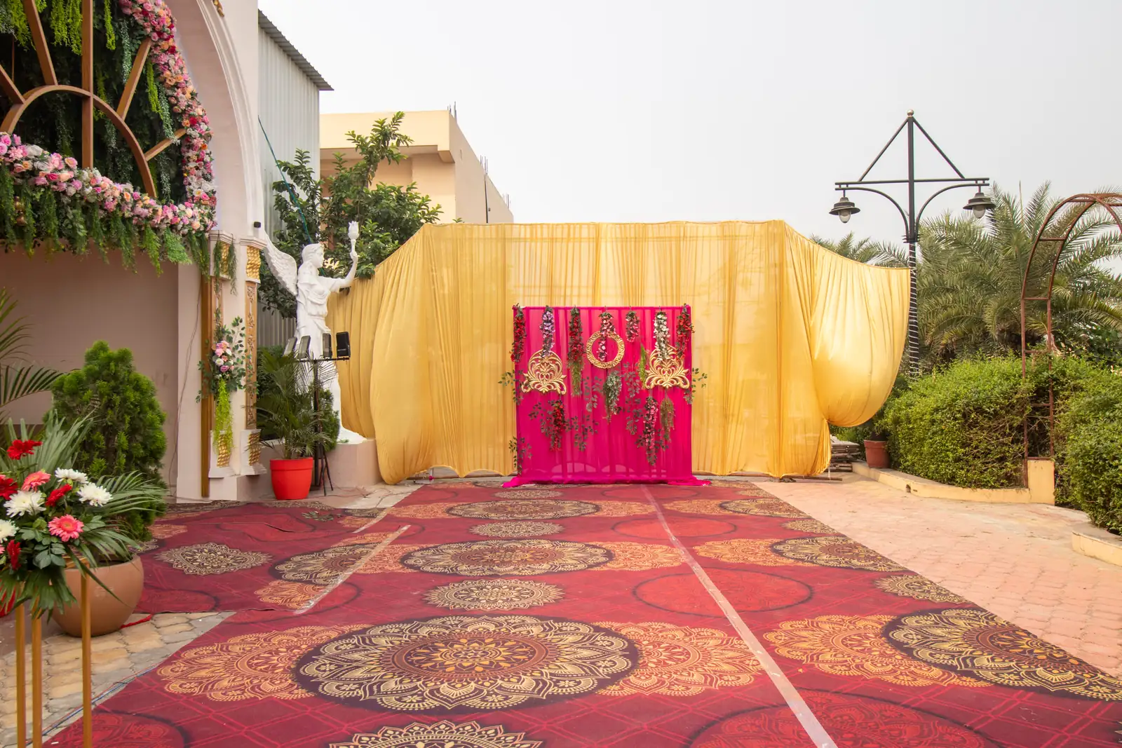 Carpeted entrance with gold drapes, a pink floral backdrop and a flower arch