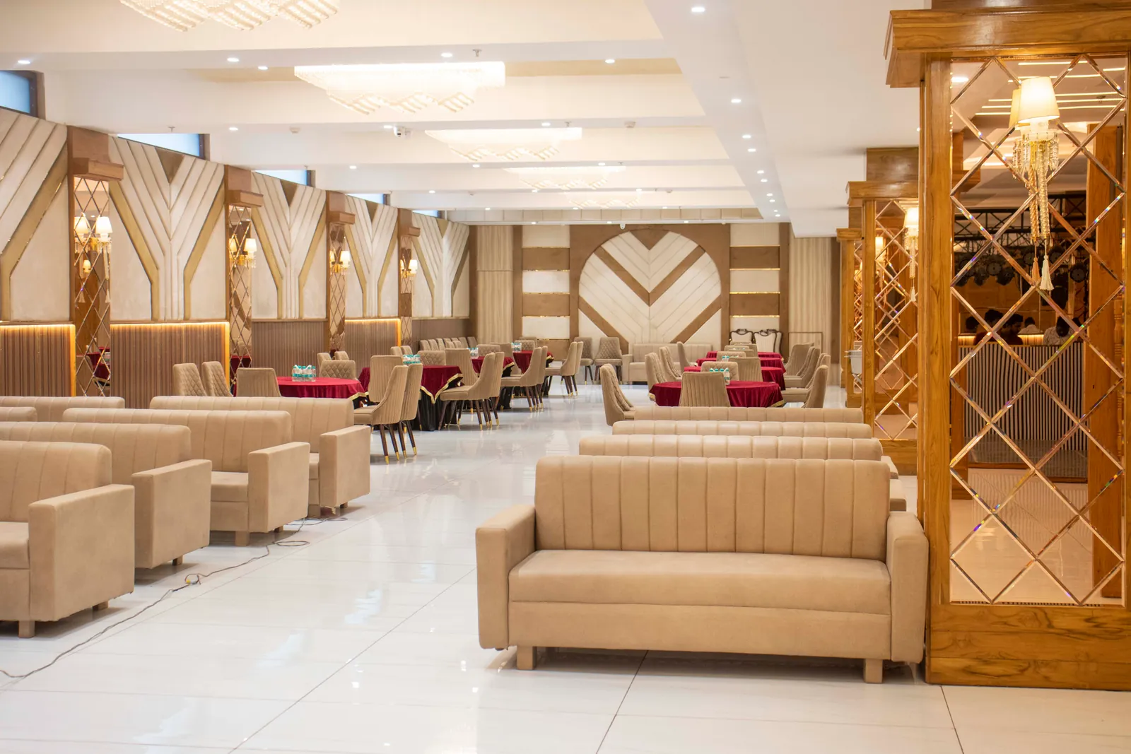 Banquet hall with rows of beige sofas under chandeliers