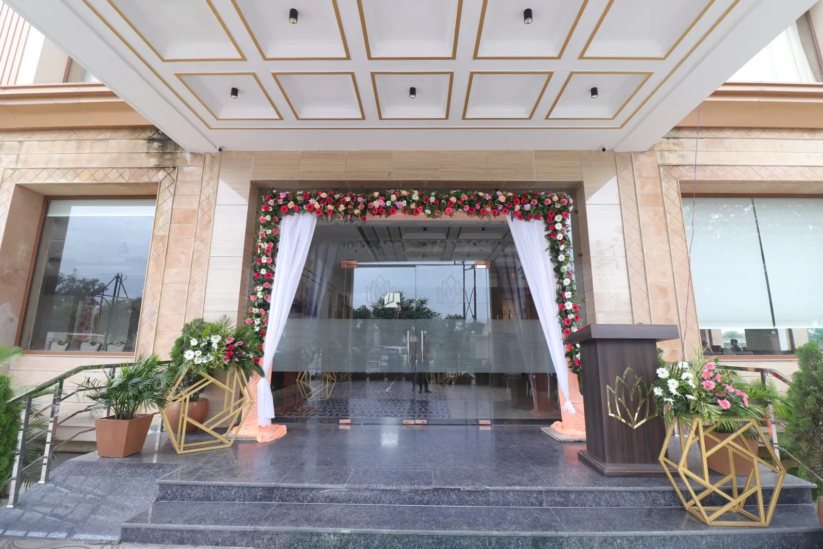 Hotel entrance steps and glass doors framed by a floral arch and white drapes