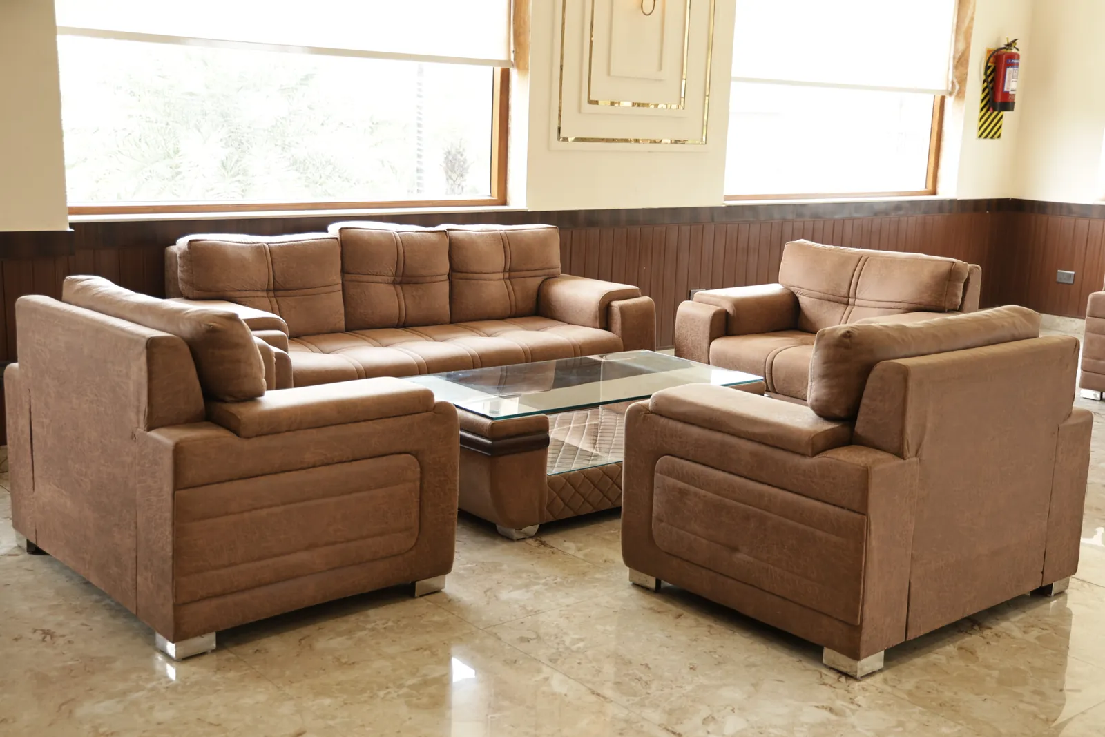 Brown sofa set around a glass coffee table by the lobby windows