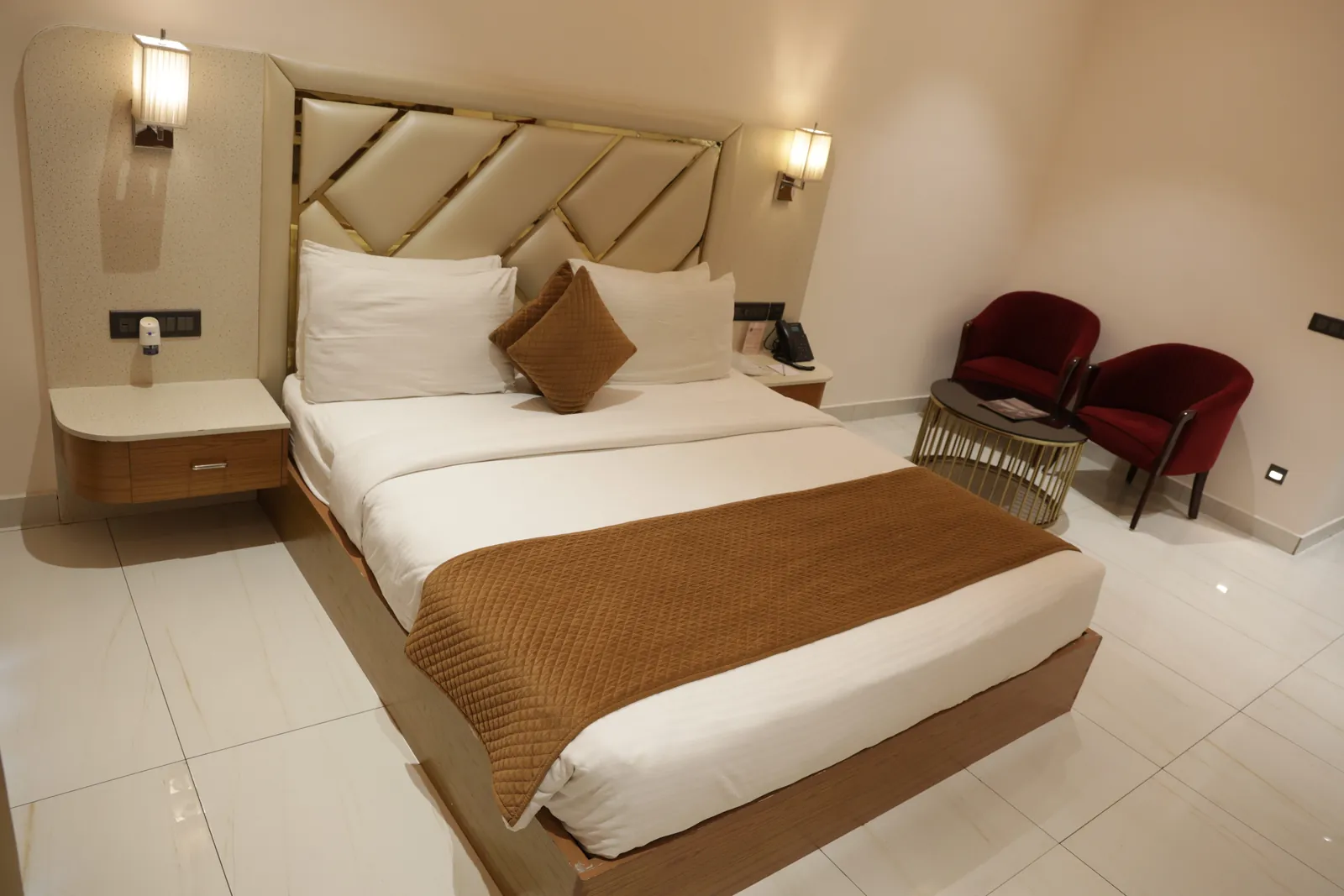Guest room with a double bed, wall lamps and two red armchairs