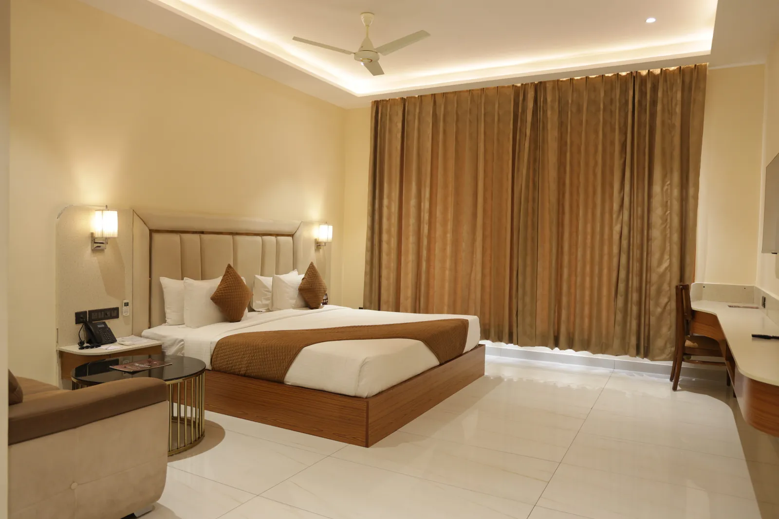 Guest room with a double bed, full-length curtains, a sofa and a work desk