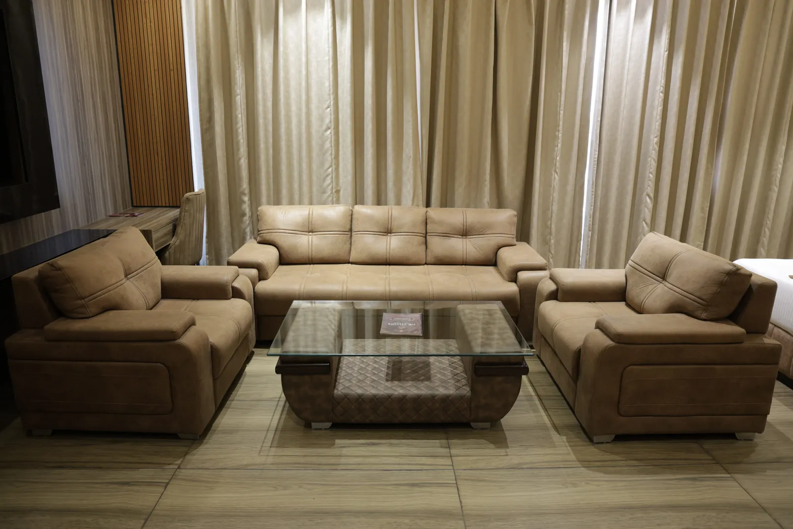 Sofa and two armchairs around a glass coffee table in front of full-length curtains
