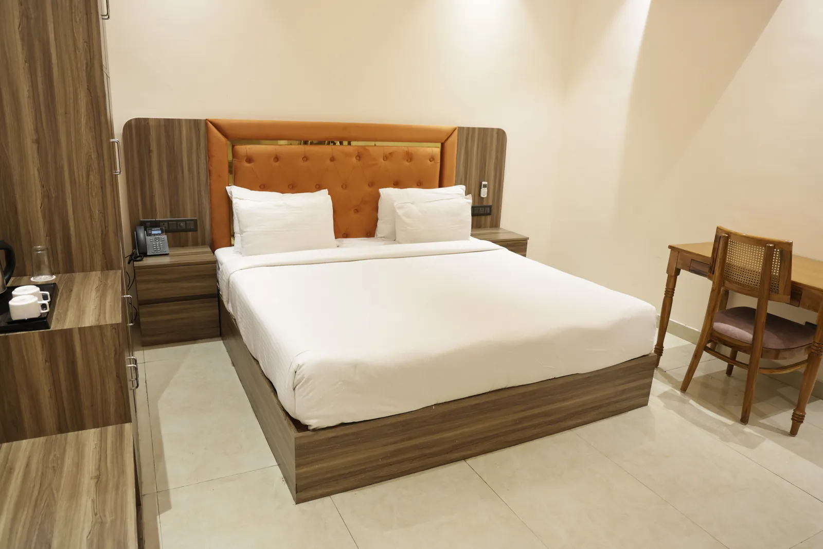 Guest room with a double bed, orange tufted headboard and a wooden writing desk