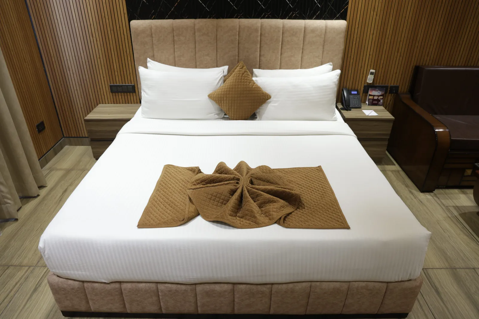 Double bed with white linen and a folded brown throw in a wood-panelled guest room