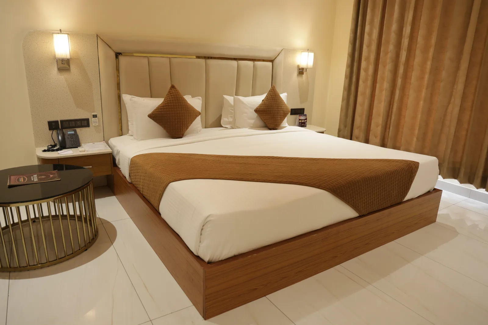 Guest room with a double bed, brown throw, wall lamps and a round side table