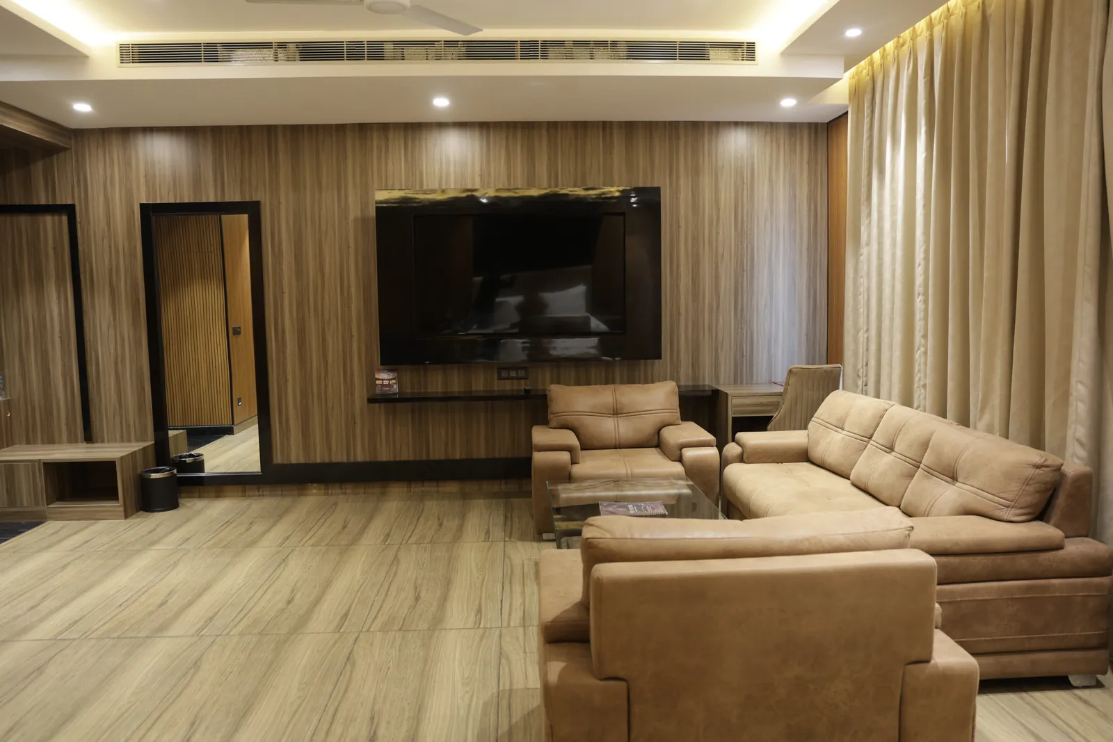 Wood-panelled room with a sofa set facing a wall-mounted television