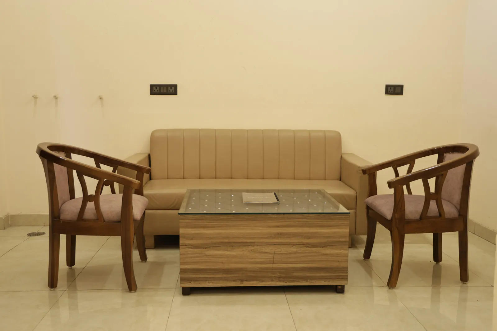 Sofa and two wooden armchairs around a coffee table in a guest room