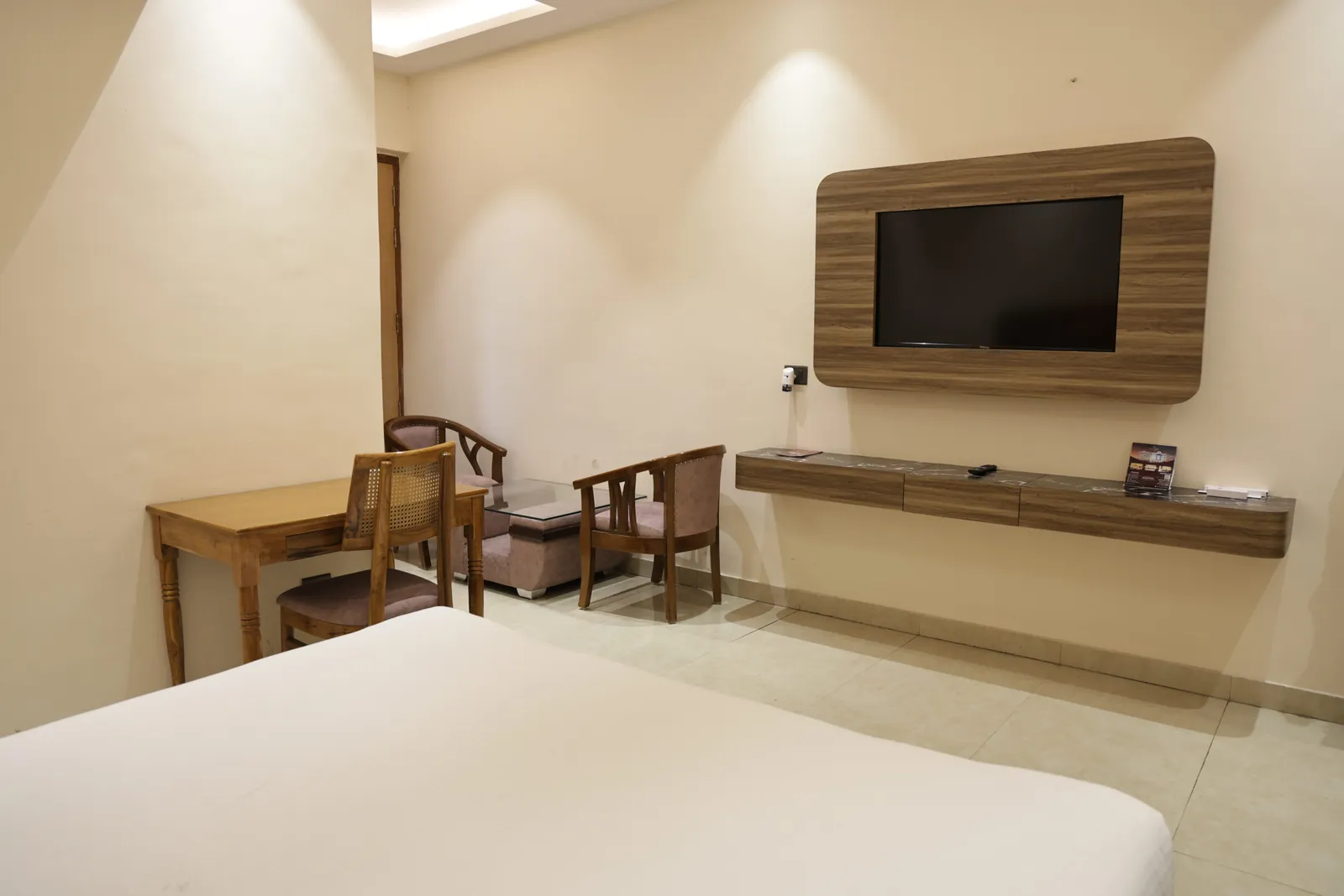 Guest room with a wall-mounted television, writing desk and two armchairs